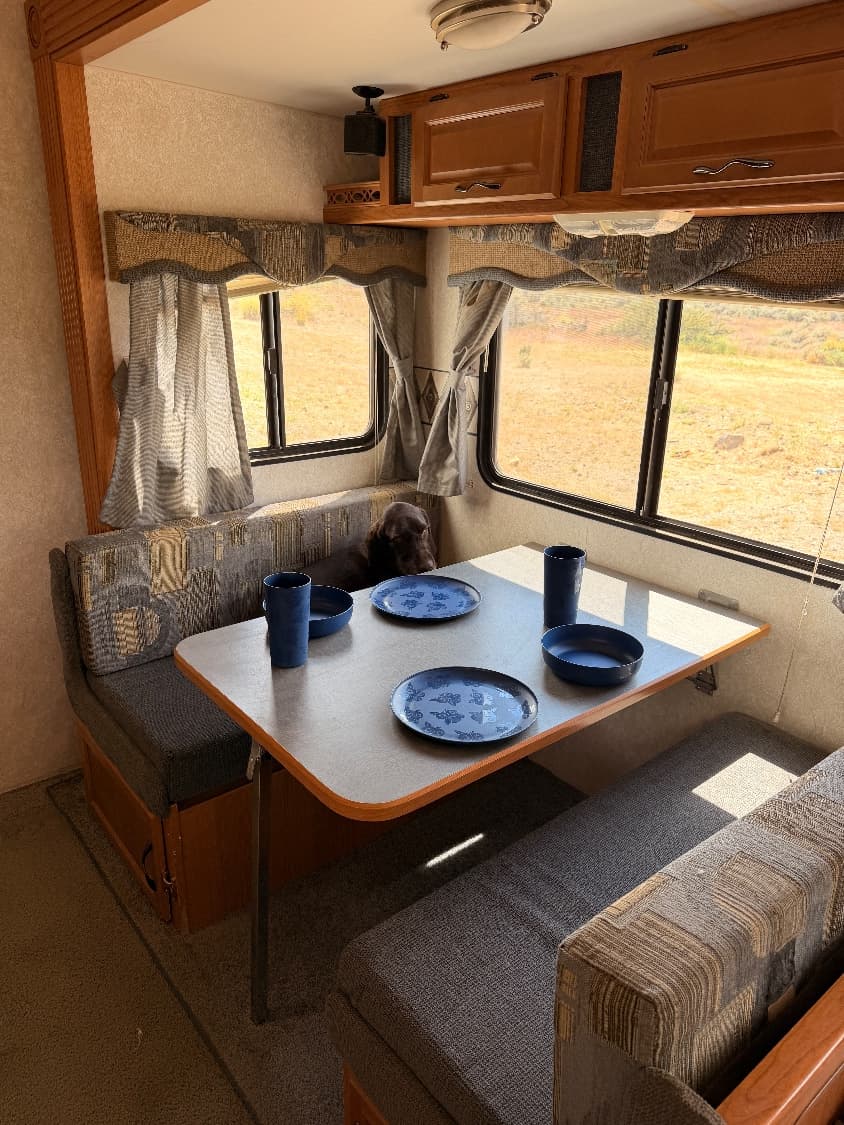 The dinette booth in The Quantum set with plates and cups, with windows looking out over the desert