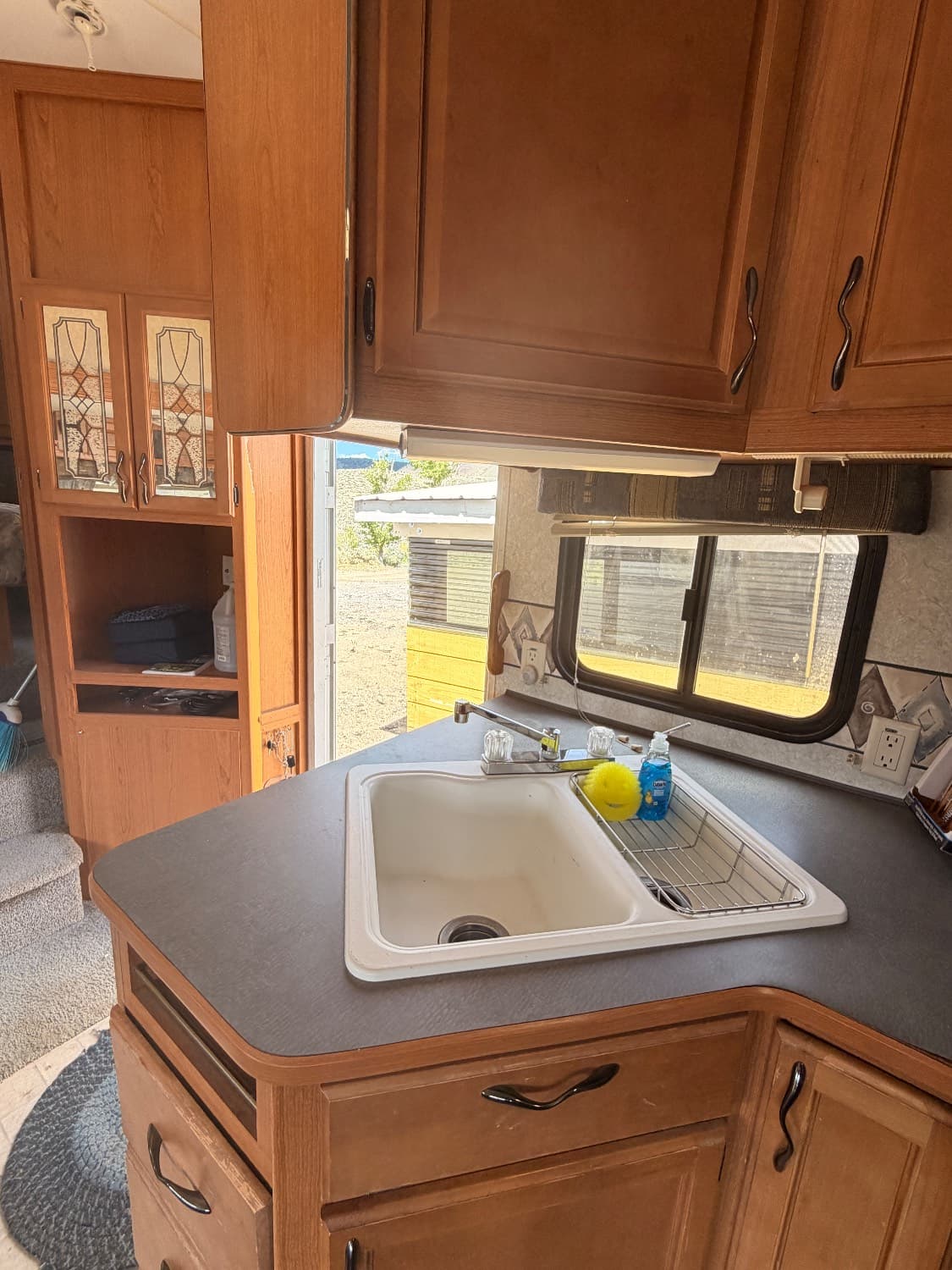 The kitchen counter and sink in The Quantum, with cabinets and drawers and the entry door open to the outside